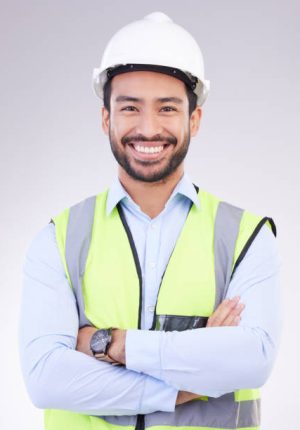 Construction worker in portrait, man with crossed arms and smile, architect or engineer in building industry on studio background. Happy male contractor, mockup and professional builder with helmet